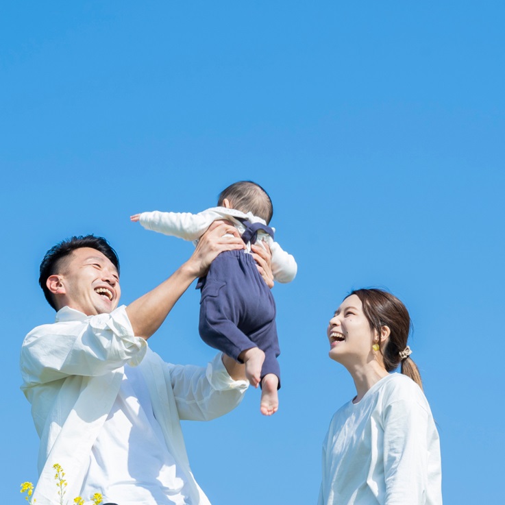 Happy parents holding baby under blue sky